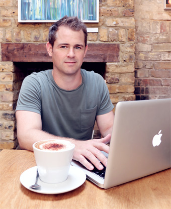 Chris typing on his laptop in a cafe